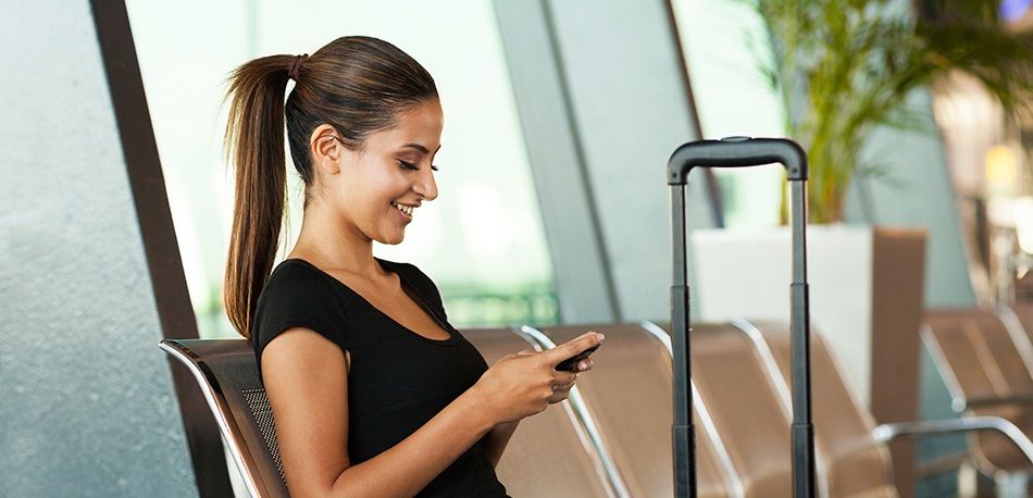 Mulher sentada num aeroporto a utilizar o smartphone